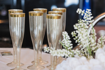 Champagne flutes lined up on pink table cloth for bridal shower