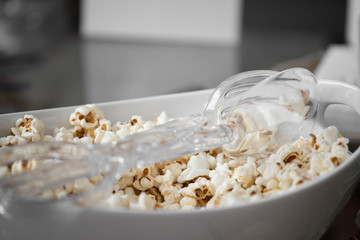 White bowl of popcorn and plastic tongs