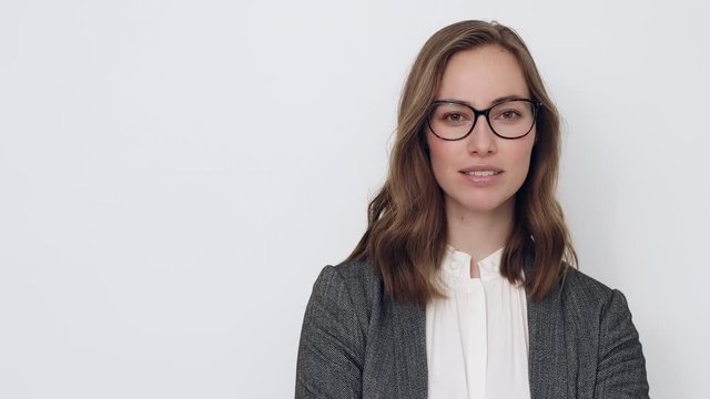 Portrait of a beautiful young business woman with glasses looking in the camera, smiling and being confident.  