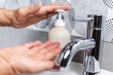 Person washing their hands with soap and hot water in the home sink wash. Cleaning the hygiene of the hand to prevent outbreaks of coronavirus.
