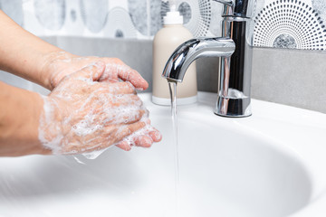  Person washing their hands with soap and hot water in the home sink wash. Cleaning the hygiene of the hand to prevent outbreaks of coronavirus. 