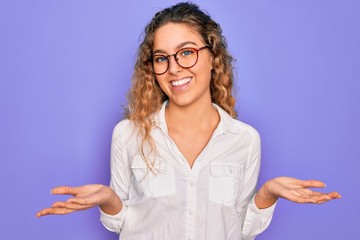 Young beautiful woman with blue eyes wearing casual shirt and glasses over purple background...