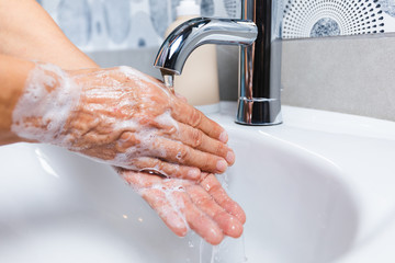  Person washing their hands with soap and hot water in the home sink wash. Cleaning the hygiene of...