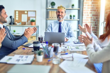Group of business workers smiling happy and confident. Working together with smile on face applauding one of them wearing king crown at the office