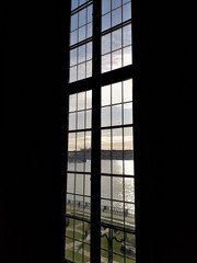 View Out of Large Window Against a Black Wall Towards Sky, Water and Park