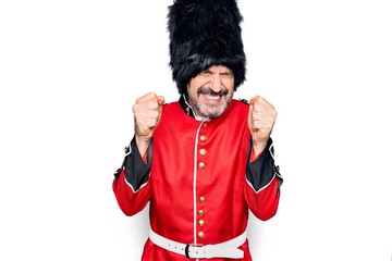 Middle age handsome wales guard man wearing traditional uniform over white background excited for success with arms raised and eyes closed celebrating victory smiling. Winner concept.