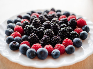 Plate of delicious and healthy blackberry, blueberries and red raspberry.