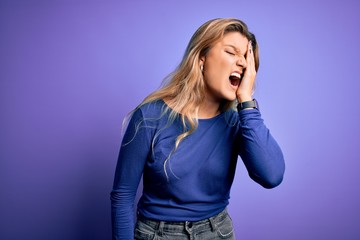 Young beautiful blonde woman wearing casual t-shirt over isolated purple background Yawning tired covering half face, eye and mouth with hand. Face hurts in pain.