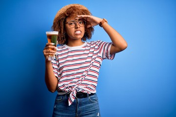 Young beautiful African American afro woman with curly hair on vacation drinking glass of beer...