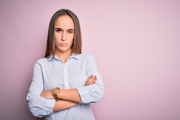 Young beautiful businesswoman wearing elegant shirt standing over isolated pink background skeptic and nervous, disapproving expression on face with crossed arms. Negative person.