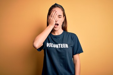 Young beautiful woman wearing volunteer t-shirt doing volunteering over yellow background Yawning...