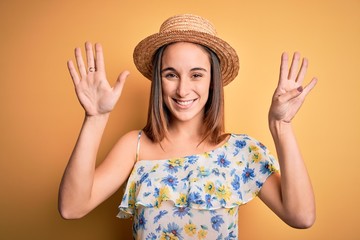 Young beautiful woman wearing casual t-shirt and summer hat over isolated yellow background showing...