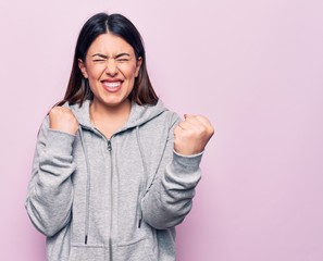 Young beautiful sporty woman wearing sportswear standing over isolated pink background celebrating surprised and amazed for success with arms raised and eyes closed