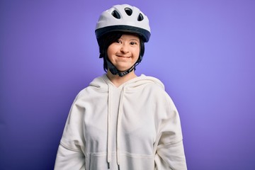 Young down syndrome cyclist woman wearing security bike helmet over purple background with a happy and cool smile on face. Lucky person.