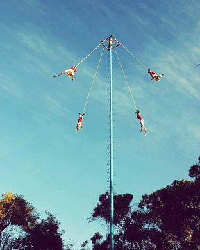 Low Angle View Of People Performing Danza De Los Voladores Ceremony Against Cloudy Sky