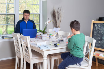 Father working from home while his child is playing in the dining  table
