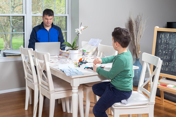 Father working from home while his child is playing in the dining  table
