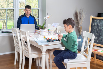 Father working from home while his child is playing in the dining  table