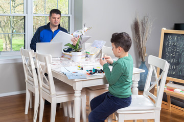 Father working from home while his children are playing in the dining  table