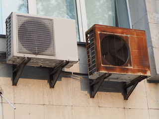 old rusty outdoor air conditioner unit on the wall of the house
