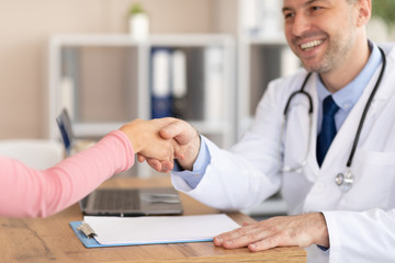 Portrait of mature doctor handshaking with patient