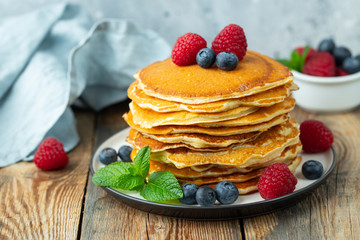 Close-up delicious pancakes, with fresh blueberries, raspberry's and honey on a light background