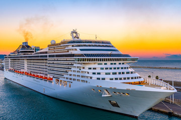 Cruise Ship docked/ anchored/ moored in Port. Amazing sunset sky glow on horizon in background.