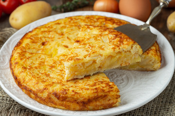 Spanish omelette with potatoes and onion, typical Spanish cuisine. Tortilla espanola. Rustic dark background