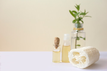 Fototapeta na wymiar Loofah washcloth next to bottles with essential oils. Skincare concept