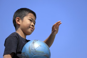 サッカーボールを抱える小学生(5年生)と青空