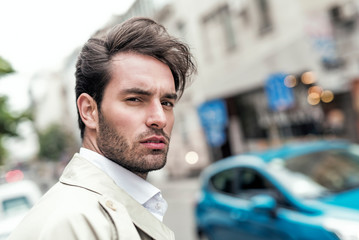 Young and charming businessman standing in the street and looking at a camera