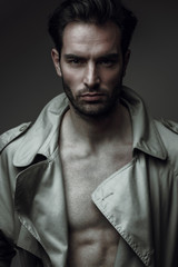 Attractive and sexy young man in coat with naked chest