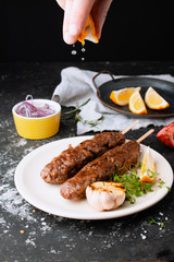 Fried sausages with the addition of herbs, vegetables, garlic, lemon and onions on the dish. Grilling food, bbq, barbecue. Homemade sausages from turkey fried in a frying pan. Adding lemon juice