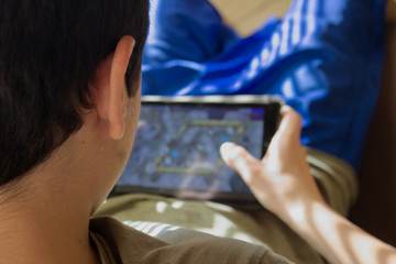 Caucasian boy sitting in an armchair checks his social networks on the tablet