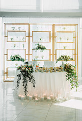 Wedding table of the bride and groom decorated with flowers and candles. Indoor wedding ceremony.
