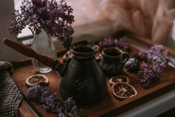 Still life of lilac flowers, coffee and chocolate on wooden tray