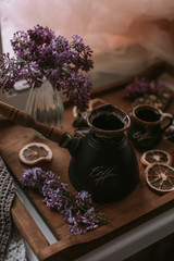 Still life of lilac flowers, coffee and chocolate on wooden tray