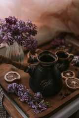 Still life of lilac flowers, coffee and chocolate on wooden tray