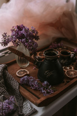 Still life of lilac flowers, coffee and chocolate on wooden tray