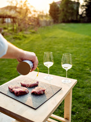 Unrecognisable man prepares meat for grilling outdoor.