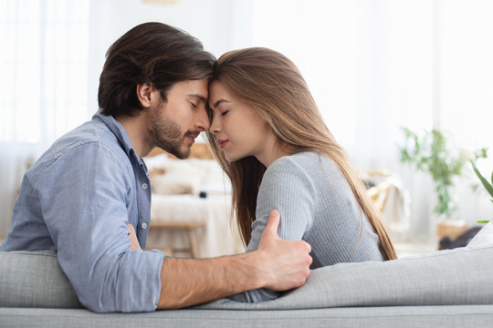 Man and woman touching each other with foreheads, home interior