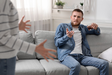 Drunk man arguing with his wife, drinking whiskey at daytime