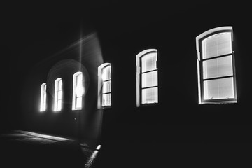 Bright light shinning through a row of windows in the middle of the night; black and white
