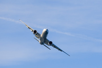 Large commercial airplane making a turn; blue sky background