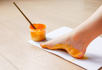 Children's foot close-up and a jar of paint.