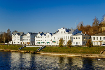 Old buildings by the river. Reflection of white houses in the water.
