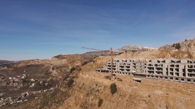 Cement resort under construction on plateau with large cranes, Faraya, Lebanon, forward aerial