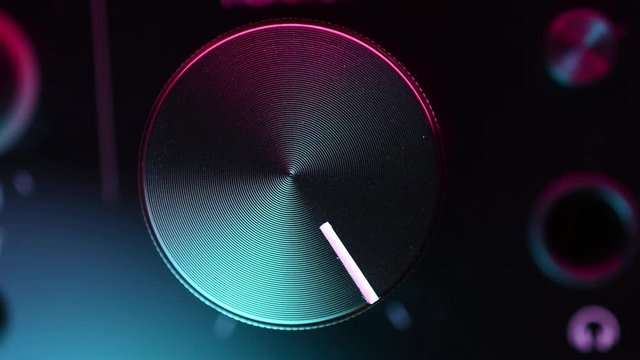 volume knob adjusting in colorful light macro closeup