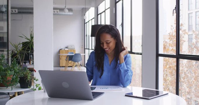 Prosperous black office worker in casual apparel using mobile device for reading business emails from company partners feeling happy with received good news, skilled accountant browsing internet
