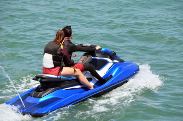 Obraz premium Young couple riding tandem on a light blue jet ski
